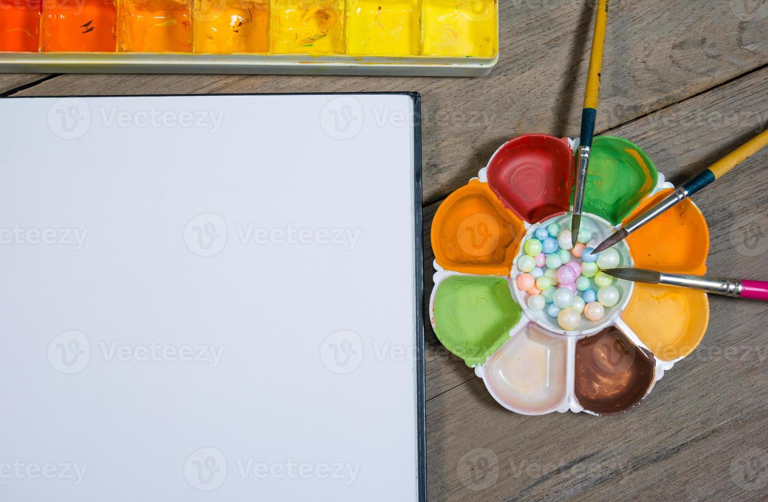 closeup open note book with tray colors on wood background photo