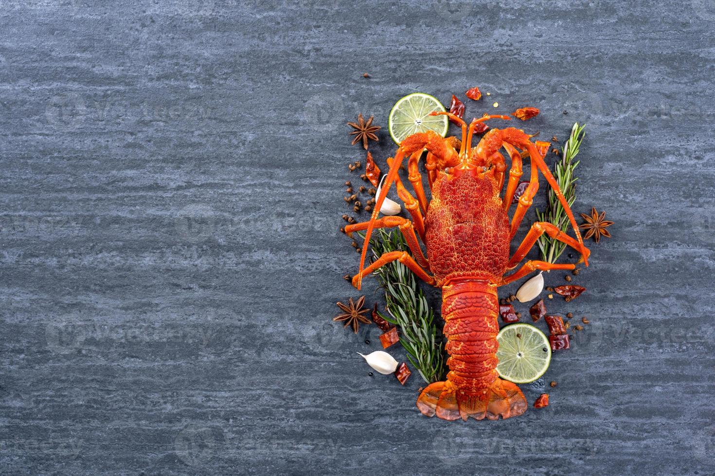Cooked boiled lobster, delicious dinner seafood meal set with knife and fork on black stone slate background, restaurant menu design, top view, overhead photo