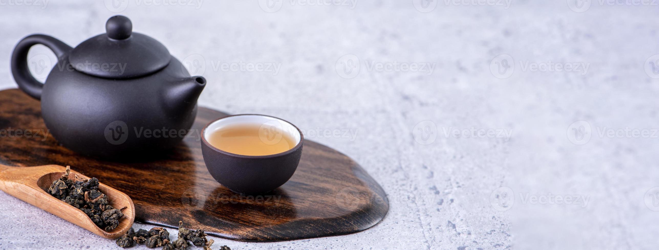 té caliente en tetera negra y tazas y hojas de té secas sobre fondo de cemento gris brillante, primer plano, concepto de diseño de espacio de copia. foto