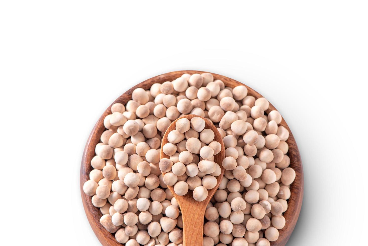 Dry raw brown tapioca pearls in a wooden bowl with spoon isolated on white background, close up, ingredient of making bubble boba milk tea. photo