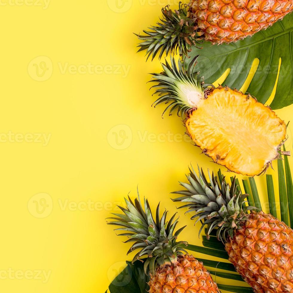Beautiful pineapple on tropical palm monstera leaves isolated on bright pastel yellow background, top view, flat lay, overhead above summer fruit. photo