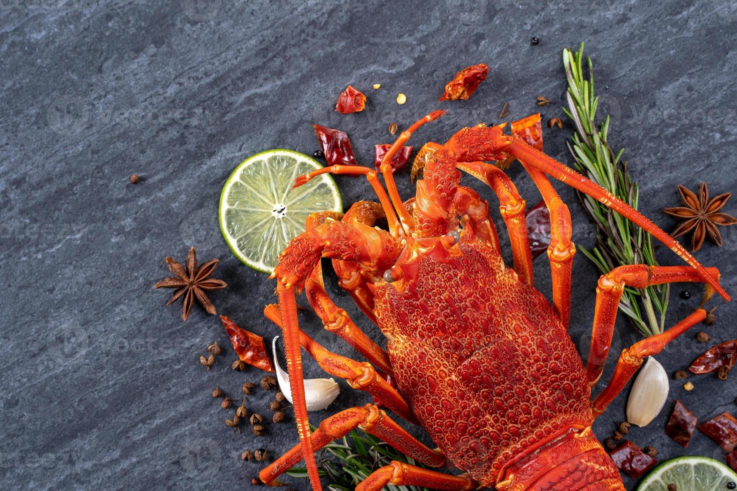 Cooked boiled lobster, delicious dinner seafood meal set with knife and fork on black stone slate background, restaurant menu design, top view, overhead photo