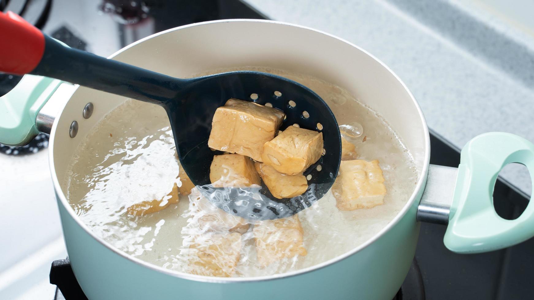 Cooking diced cubed dried tofu on gas stove in home kitchen, lifestyle, closeup. photo