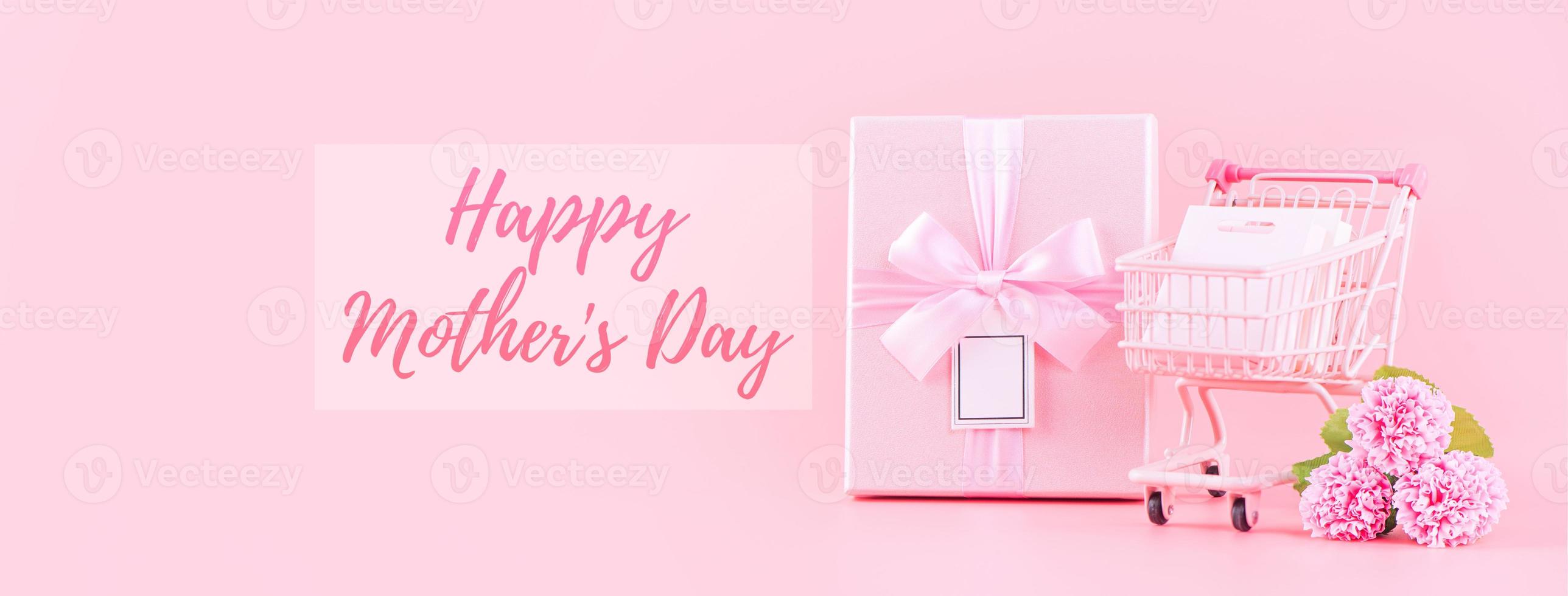 Mother's Day holiday gift design concept, pink carnation flower bouquet with wrapped box isolated on light pink background, copy space. photo