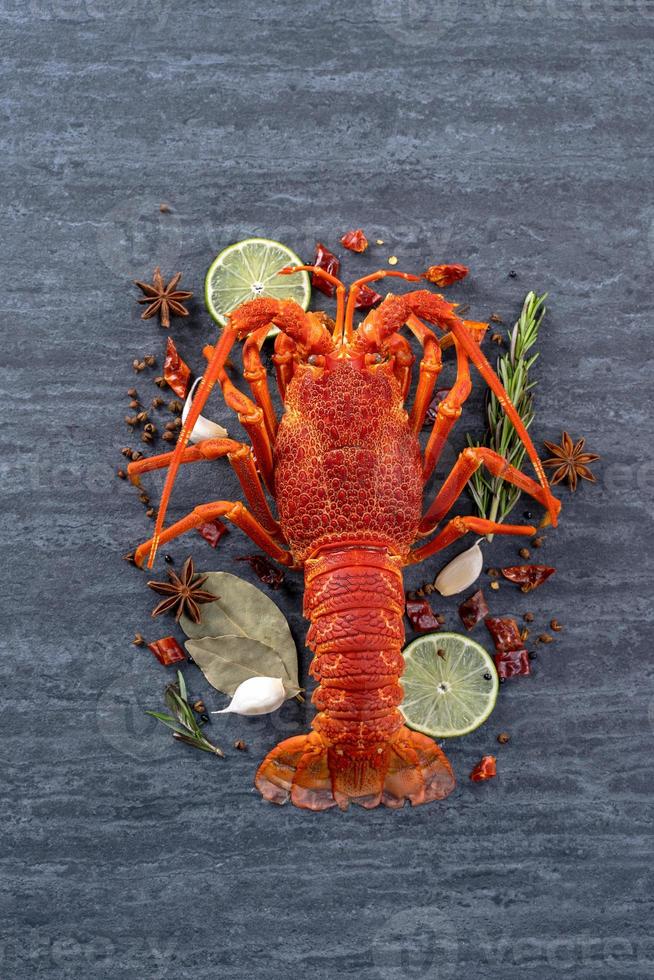 Cooked boiled lobster, delicious dinner seafood meal set with knife and fork on black stone slate background, restaurant menu design, top view, overhead photo