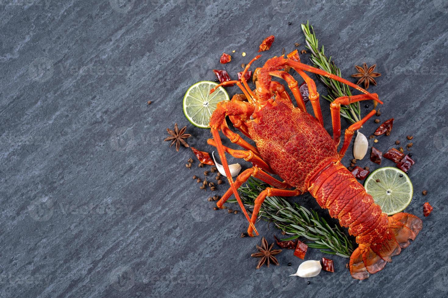 Langosta hervida cocida, deliciosa cena de marisco con cuchillo y tenedor sobre fondo de pizarra de piedra negra, diseño de menú de restaurante, vista superior, sobrecarga foto