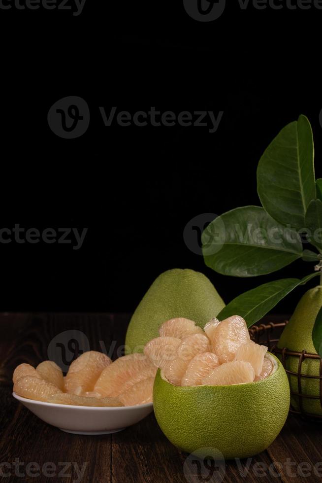 Fresh pomelo, pummelo, grapefruit, shaddock on wooden table over black background, close up, copy space. Fruit for Mid-autumn festival. photo