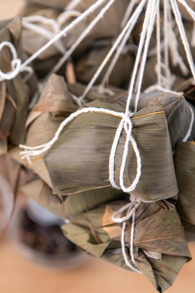 dumpling de arroz - comida china zongzi en un vapor sobre una mesa de madera con pared de ladrillo rojo, fondo de ventana en casa para el concepto del festival del bote del dragón, de cerca. foto