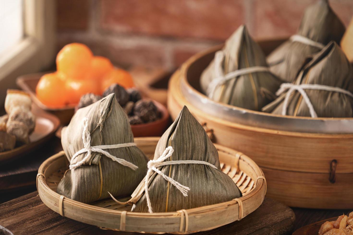 zongzi - bola de masa hervida de arroz chino zongzi en un vapor sobre una mesa de madera con ladrillo rojo, fondo de ventana en casa para el concepto del festival del bote del dragón, de cerca. foto