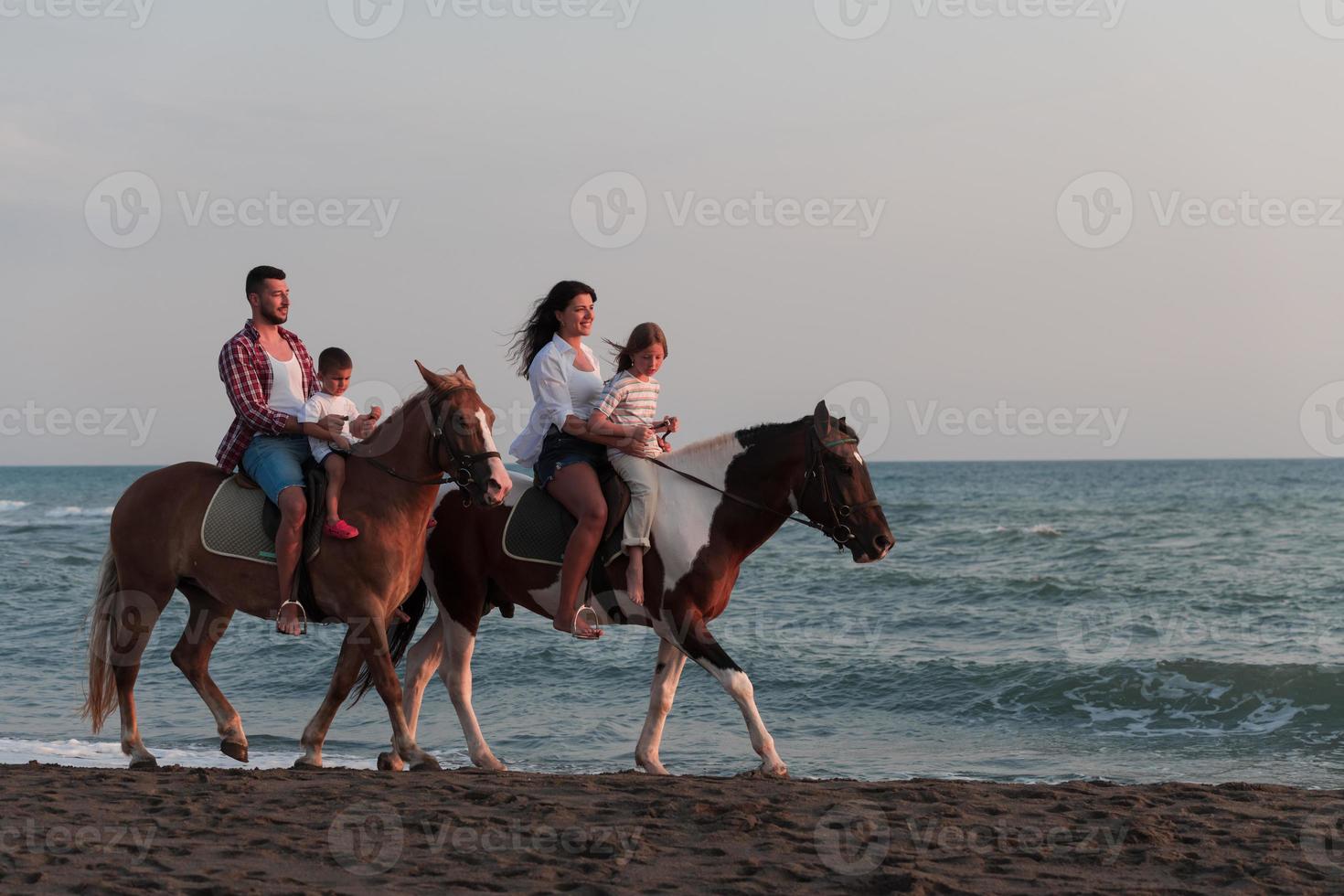 la familia pasa tiempo con sus hijos mientras montan a caballo juntos en una playa de arena. enfoque selectivo foto