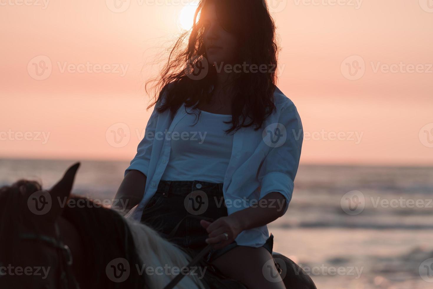 Woman in summer clothes enjoys riding a horse on a beautiful sandy beach at sunset. Selective focus photo