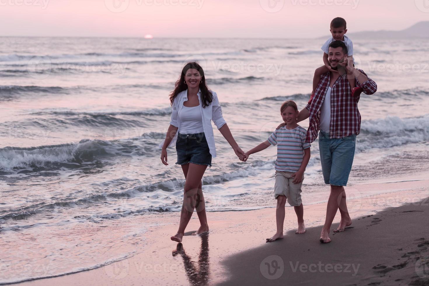 reuniones familiares y socializar en la playa al atardecer. la familia camina por la playa de arena. enfoque selectivo foto