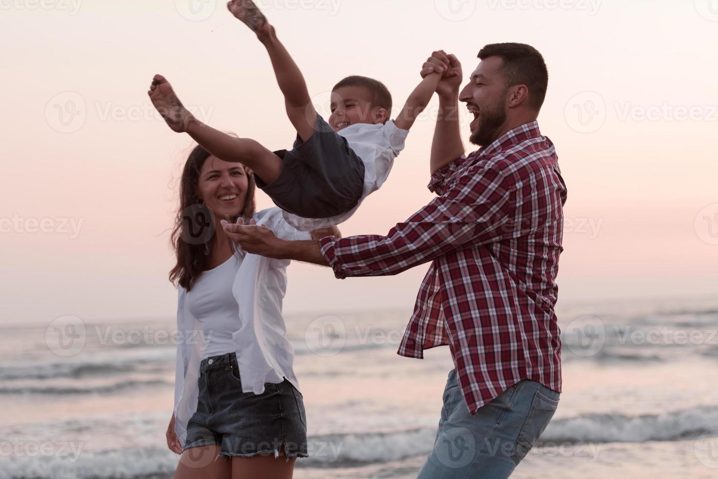 The family enjoys their vacation as they walk the sandy beach with their son. Selective focus photo