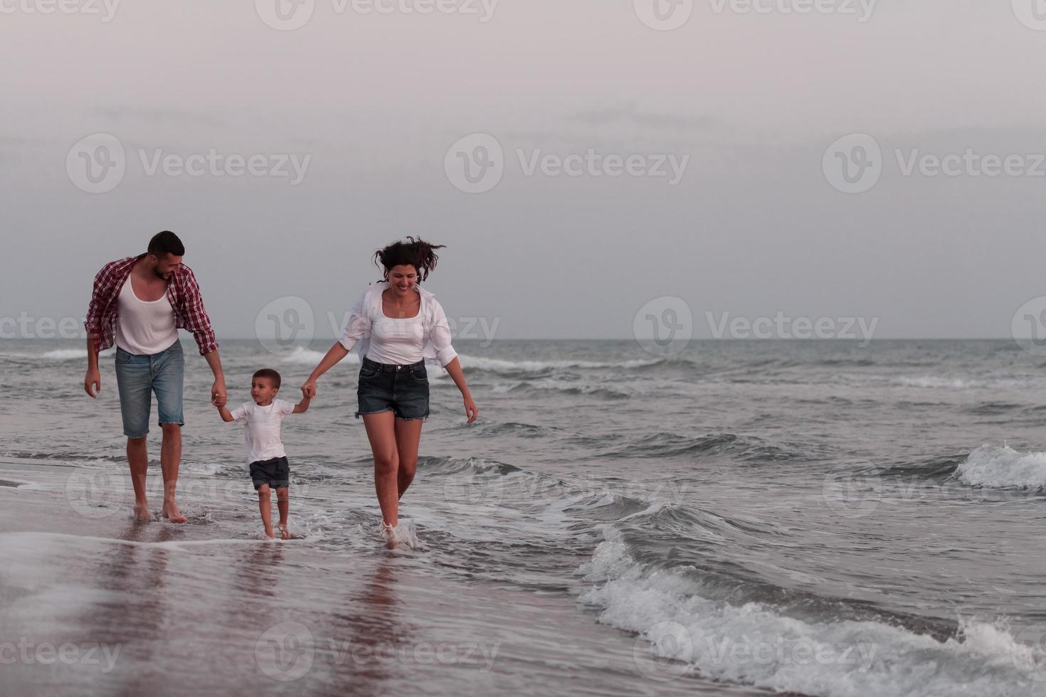 The family enjoys their vacation as they walk the sandy beach with their son. Selective focus photo