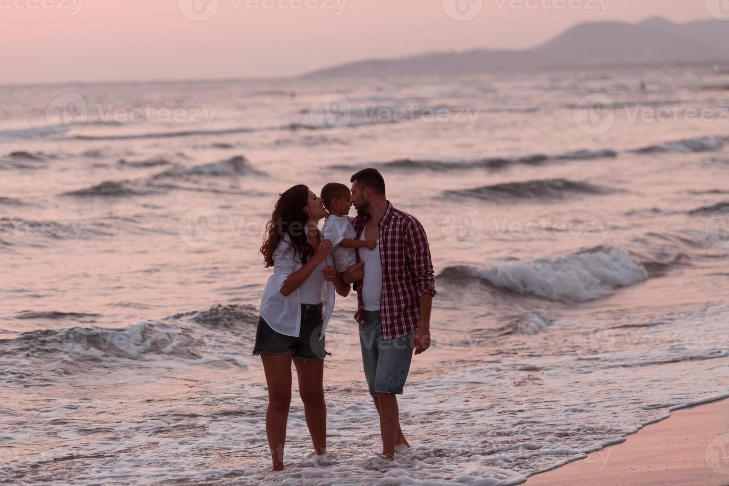 The family enjoys their vacation as they walk the sandy beach with their son. Selective focus photo