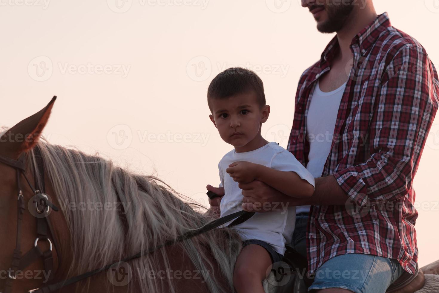 Father and son enjoy riding horses together by the sea. Selective focus photo