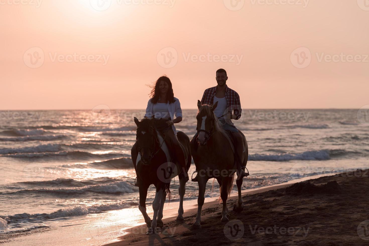 a loving couple in summer clothes riding a horse on a sandy beach at sunset. Sea and sunset in the background. Selective focus photo