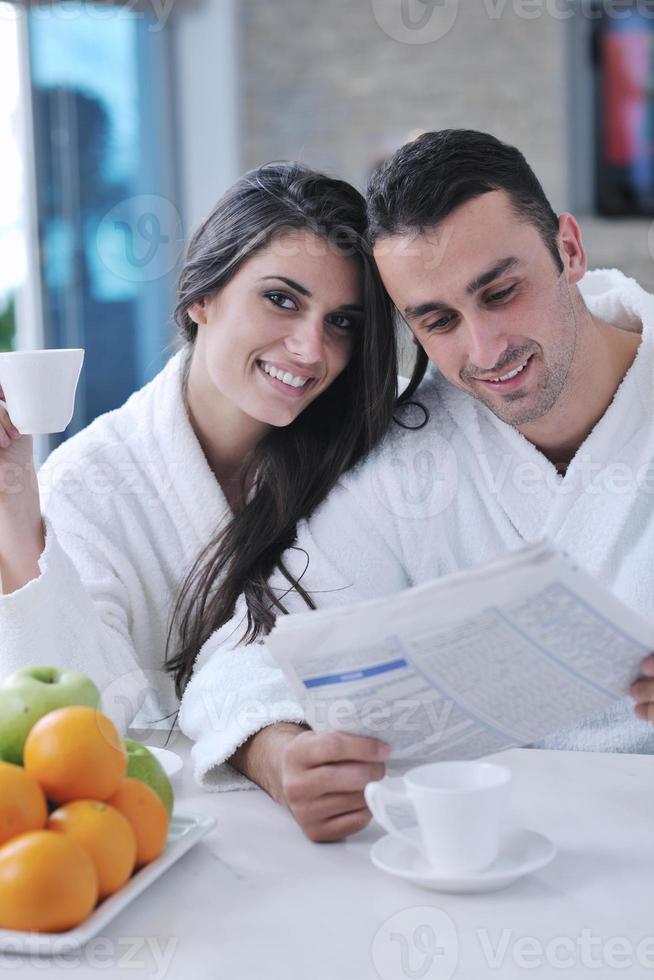 Happy couple reading the newspaper in the kitchen at breakfast photo