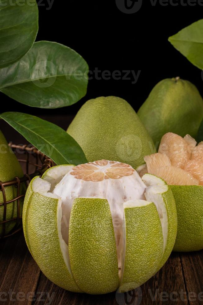 Fresh pomelo, pummelo, grapefruit, shaddock on wooden table over black background, close up, copy space. Fruit for Mid-autumn festival. photo