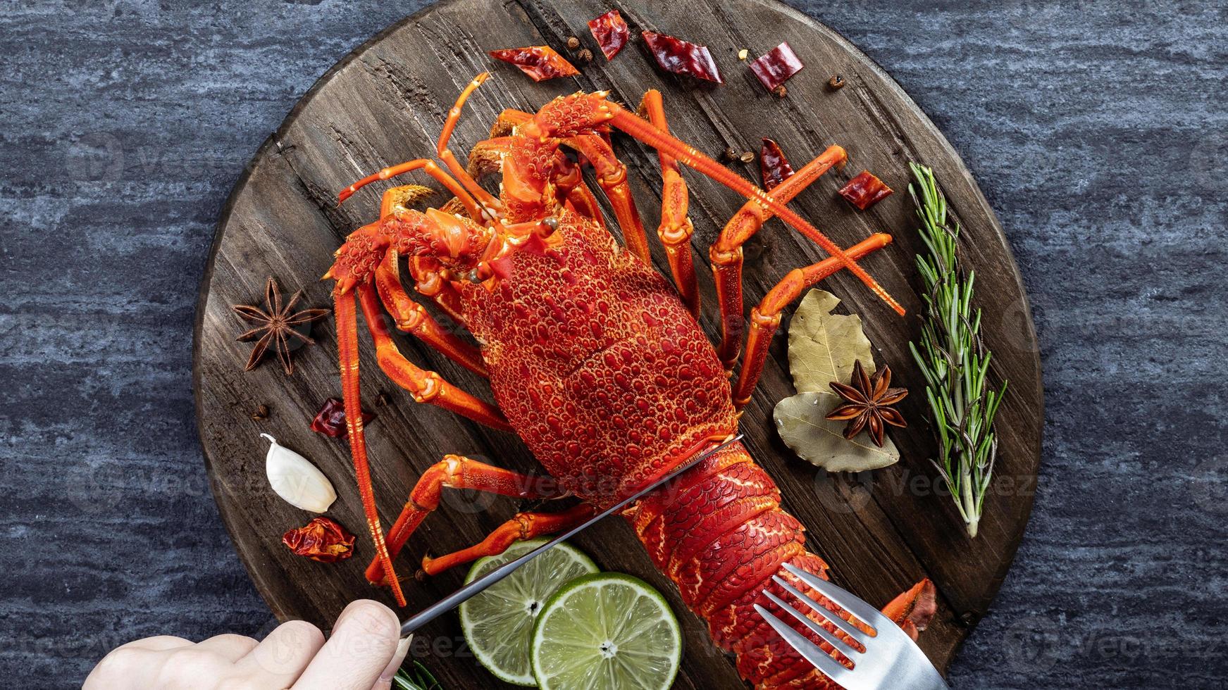 Cooked boiled lobster, delicious dinner seafood meal set with knife and fork on black stone slate background, restaurant menu design, top view, overhead photo