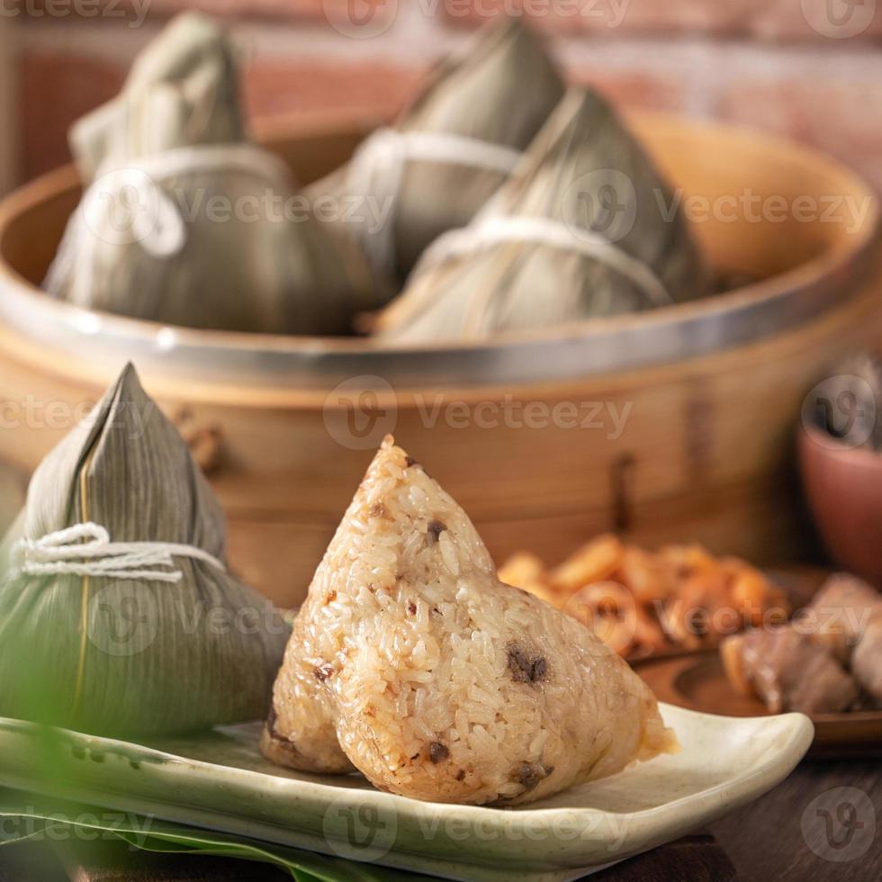 dumpling de arroz, zongzi - dumpling de arroz chino zongzi en un vapor sobre una mesa de madera con ladrillo rojo, fondo de ventana en casa para el concepto del festival del bote del dragón, de cerca. foto