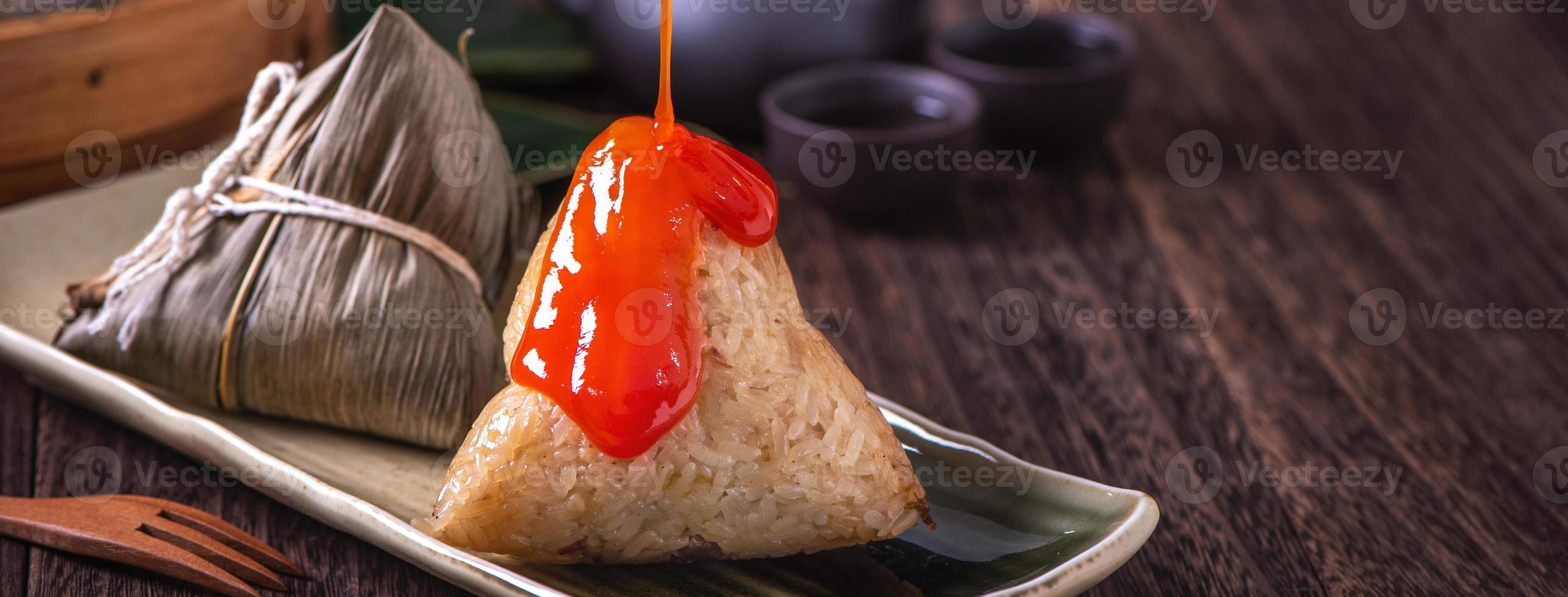 Rice dumpling, zongzi - Dragon Boat Festival, Bunch of Chinese traditional cooked food in steamer on wooden table over black background, close up, copy space photo