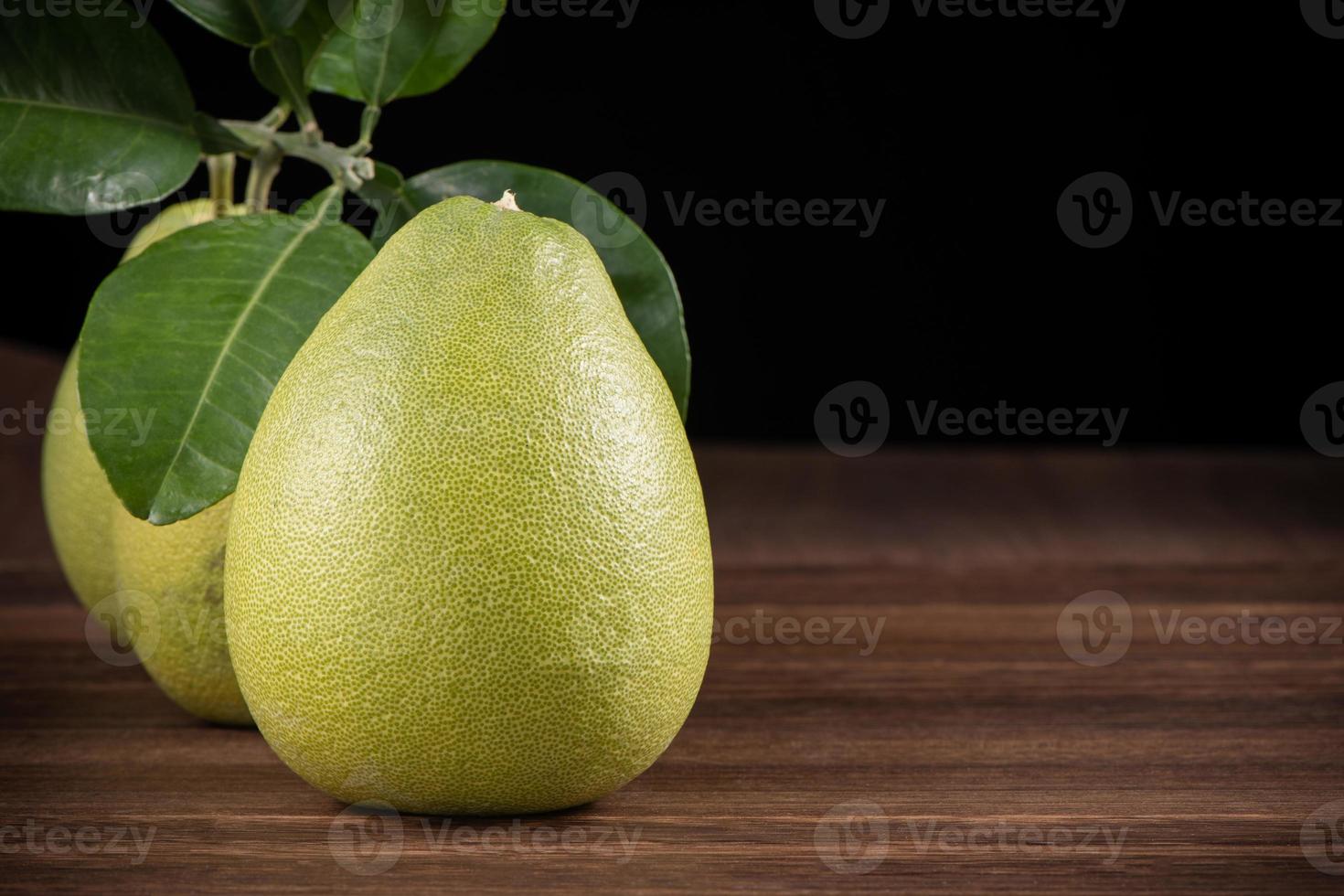 Fresh pomelo, pummelo, grapefruit, shaddock on wooden table over black background, close up, copy space. Fruit for Mid-autumn festival. photo