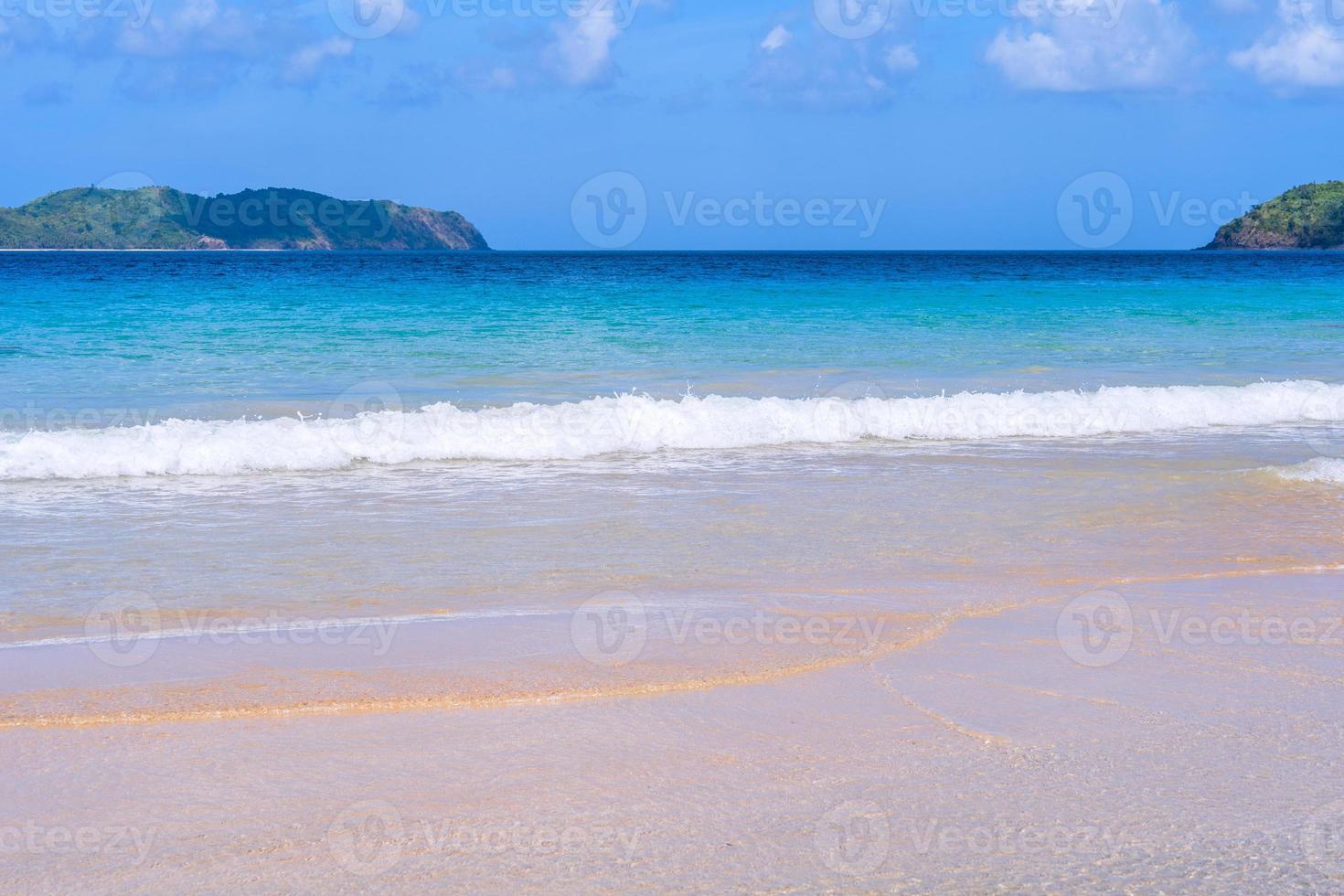 Beautiful amazing gold colored sandy beach with soft waves isolated with sunny blue sky. Concept of tropical calm tourism idea, copy space, close up photo