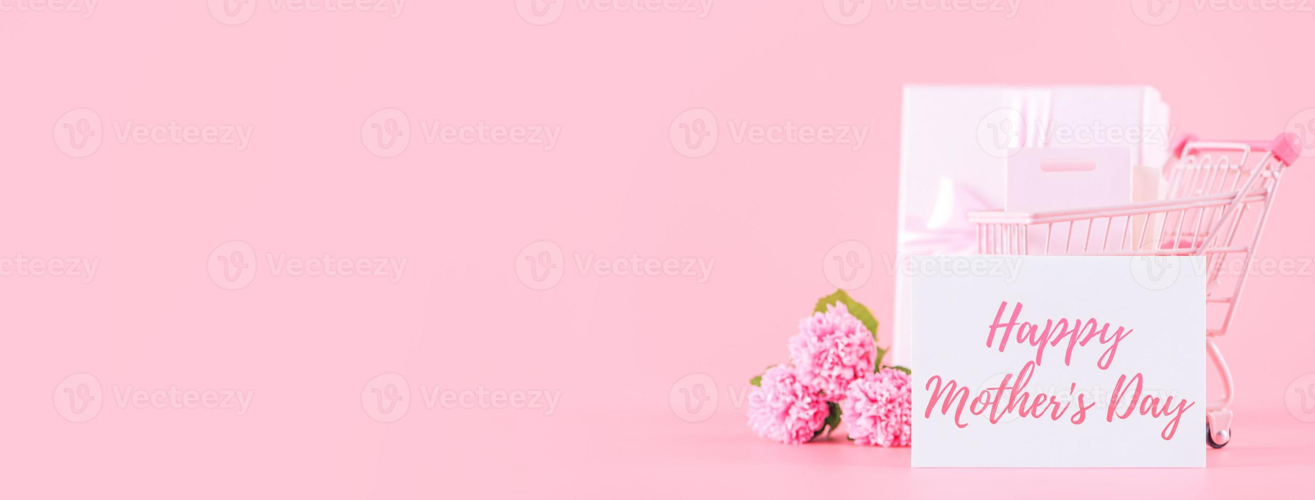 Mother's Day holiday gift design concept, pink carnation flower bouquet with wrapped box isolated on light pink background, copy space. photo