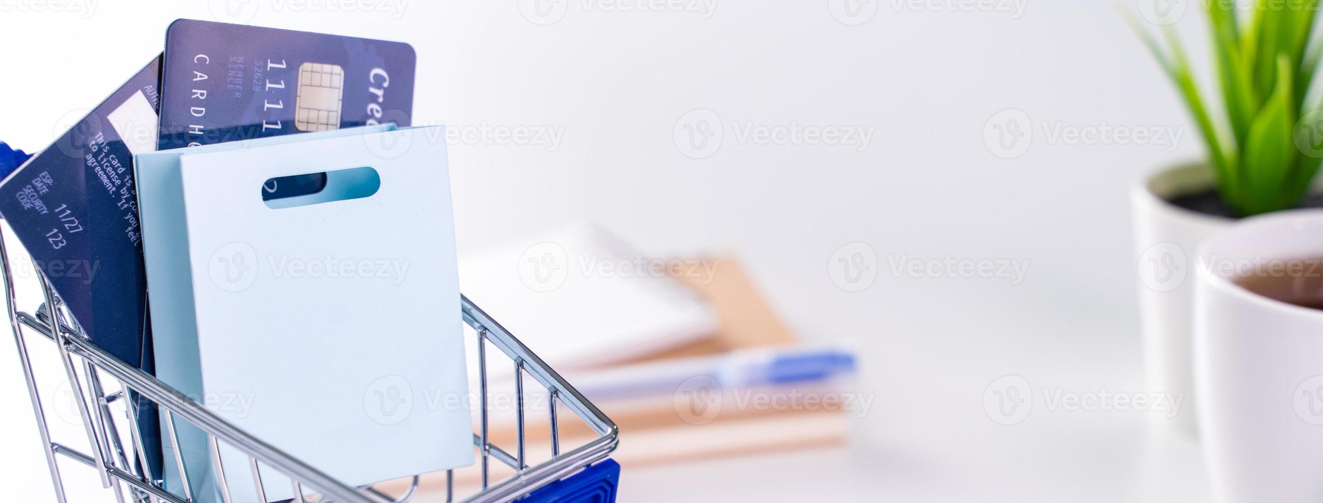 Office online paying, stay home shopping, electronic payment with credit card concept, laptop on white table background with shop cart, close up. photo