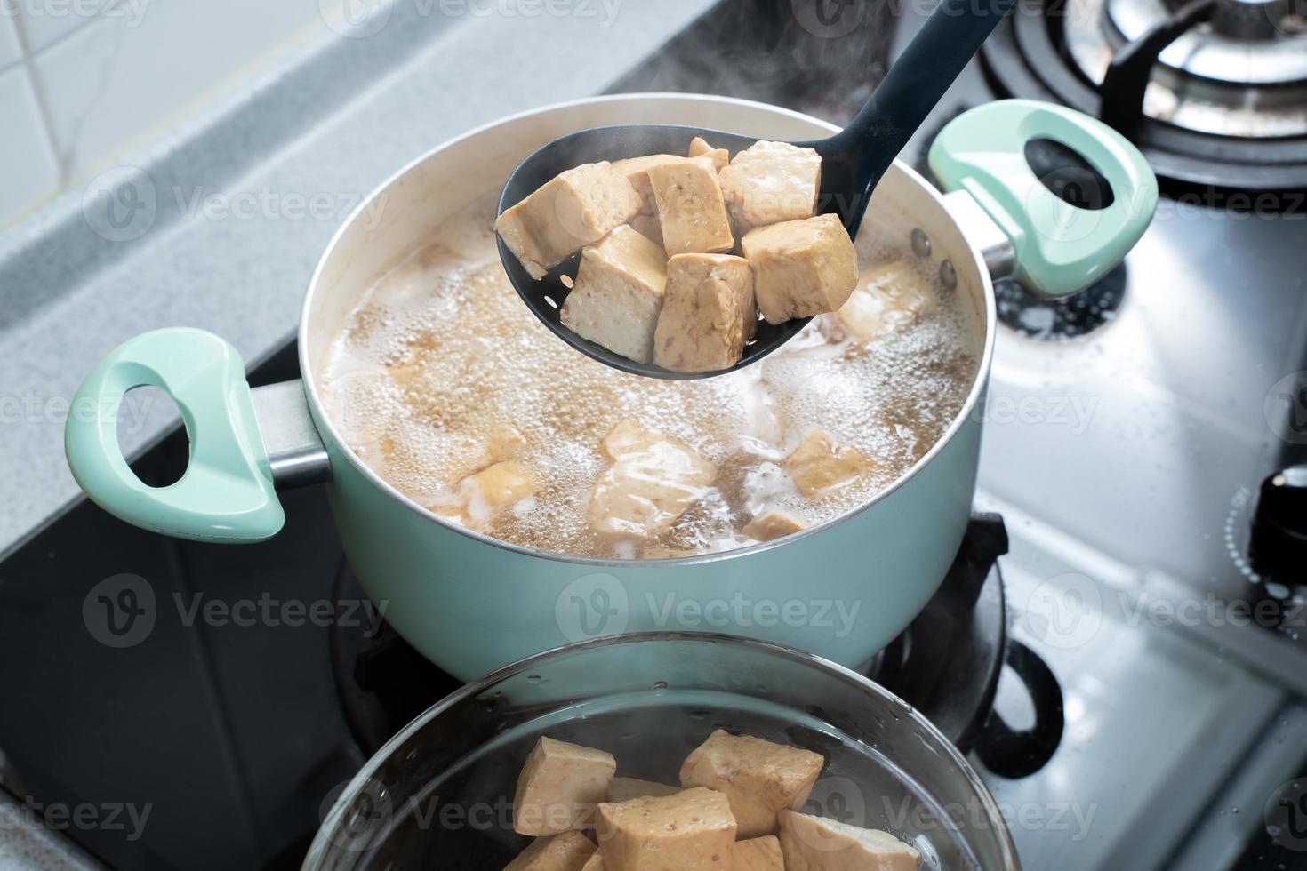cocinar tofu seco en cubitos en una estufa de gas en la cocina casera, estilo de vida, primer plano. foto