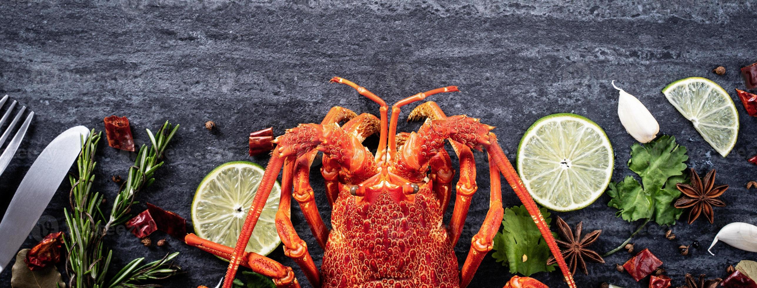 Langosta hervida cocida, deliciosa cena de marisco con cuchillo y tenedor sobre fondo de pizarra de piedra negra, diseño de menú de restaurante, vista superior, sobrecarga foto