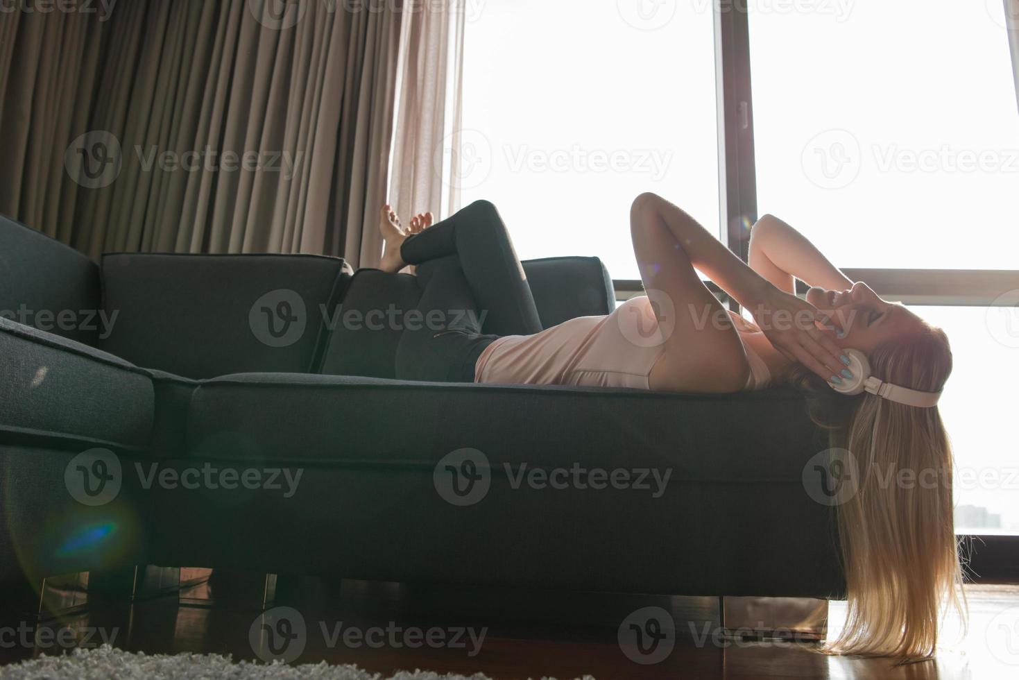 Lovely Blond Woman Listening To Music while resting on couch photo