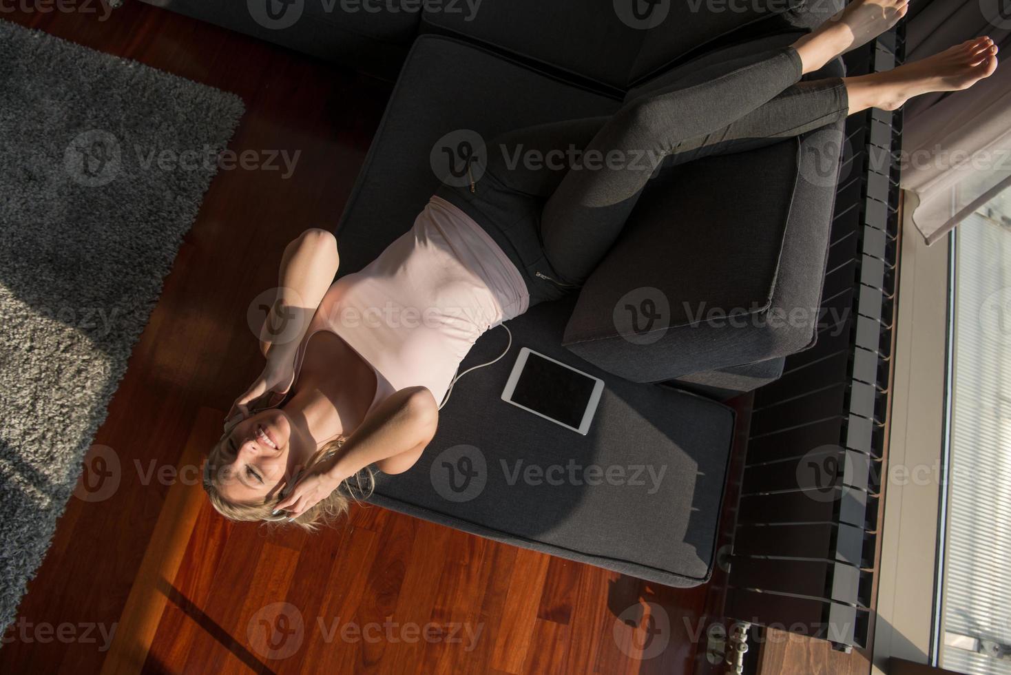 encantadora mujer rubia escuchando música mientras descansa en el sofá foto