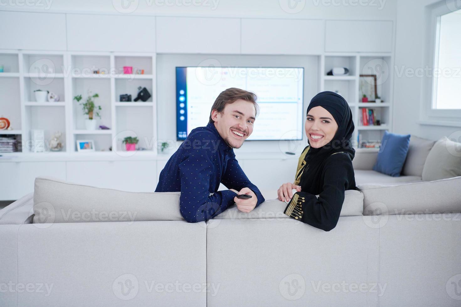 young muslim couple watching TV together photo