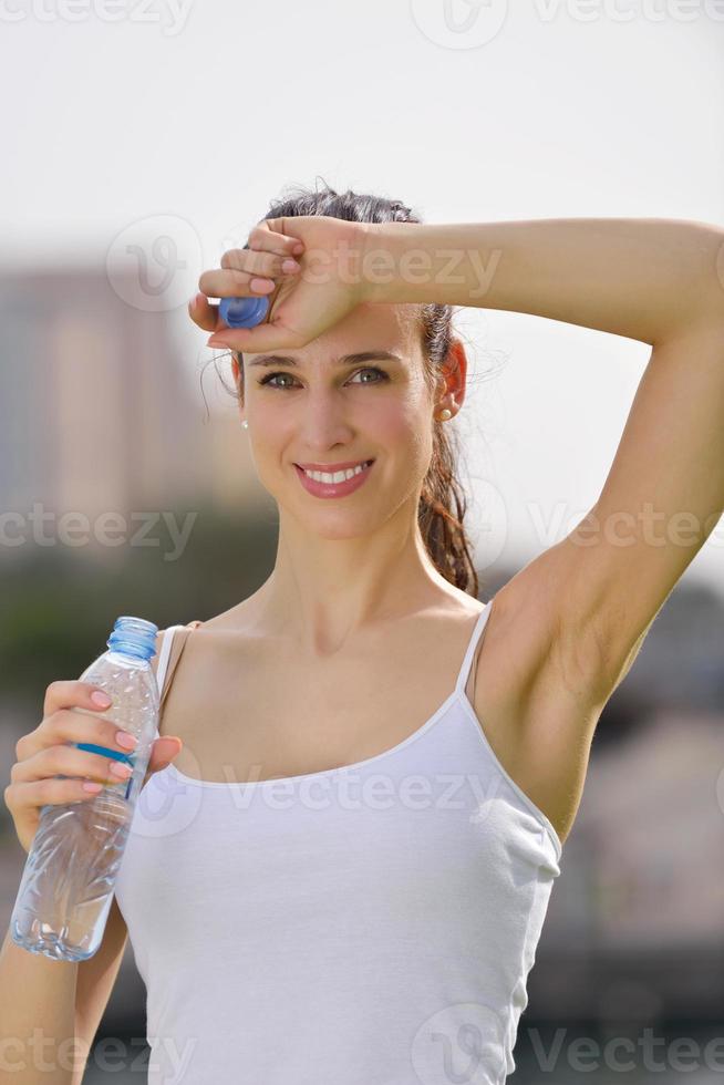 Young beautiful woman drinking water after fitness exercise photo