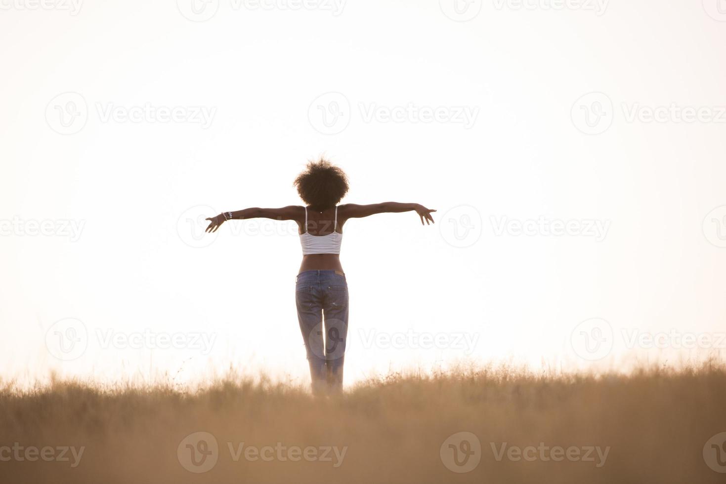 young black girl dances outdoors in a meadow photo