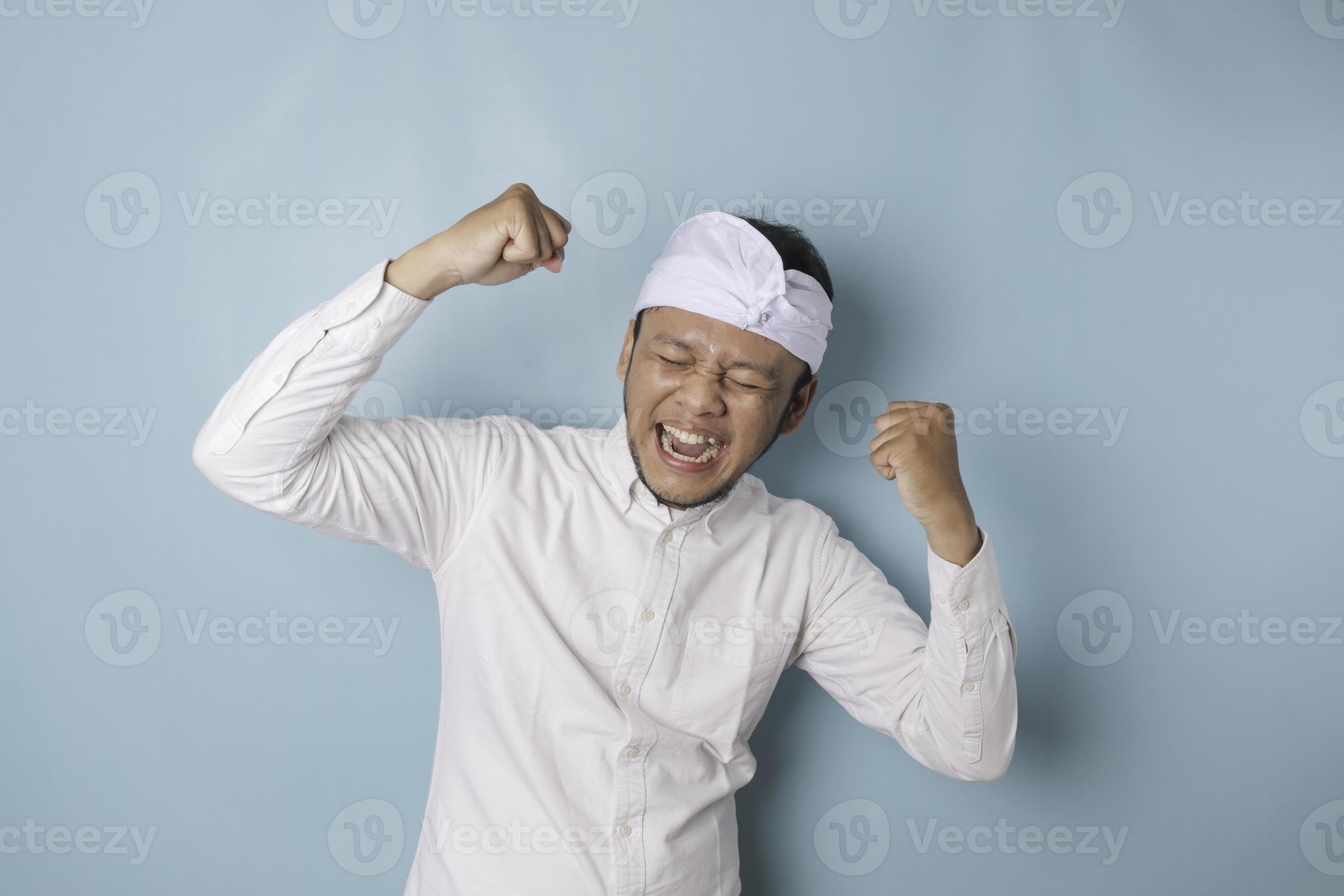 A young Balinese man with a happy successful expression wearing udeng