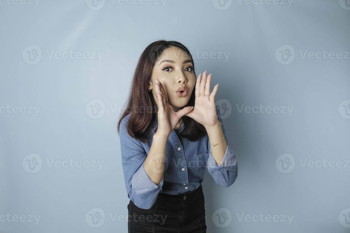 Young beautiful woman wearing a blue shirt shouting and screaming loud to the side with a hand on her mouth. communication concept. photo
