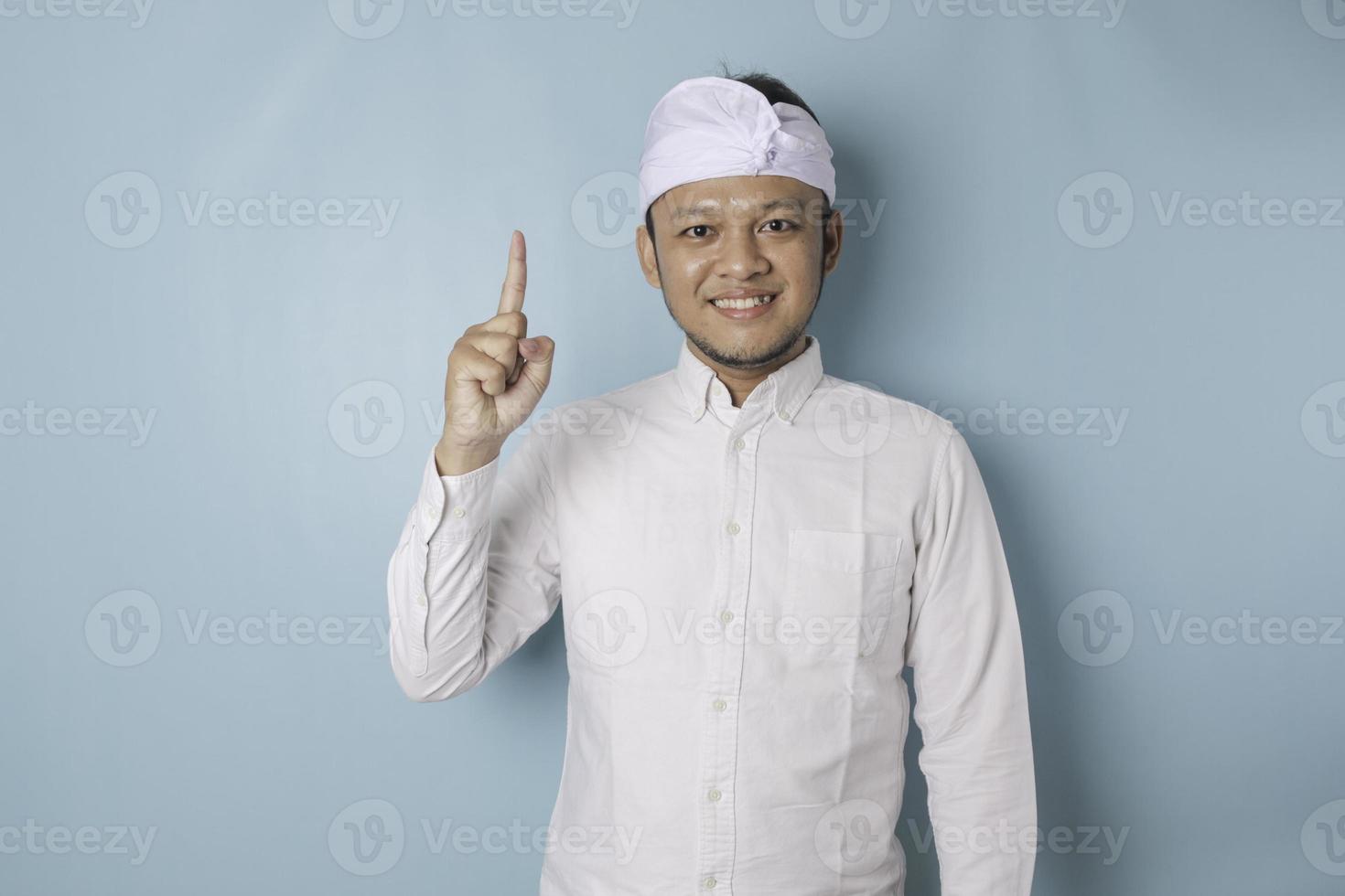 Excited Balinese man wearing udeng or traditional headband and white shirt giving number 12345 by hand gesture photo