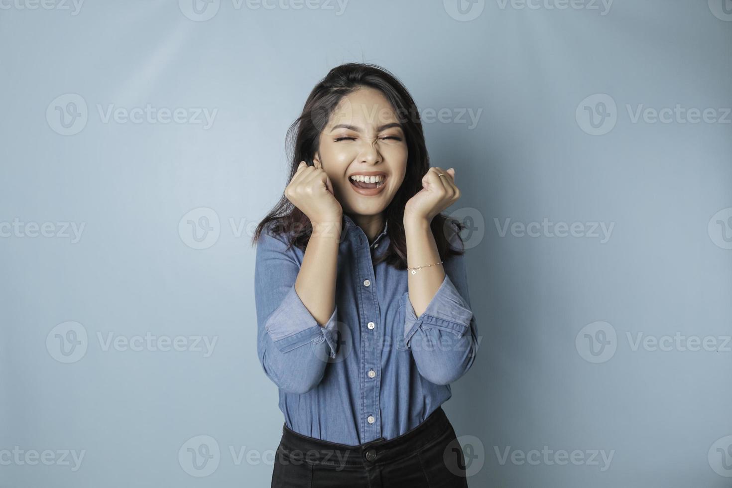 un retrato de una linda mujer asiática con una camisa azul y sintiéndose emocionada y aislada por un fondo azul foto