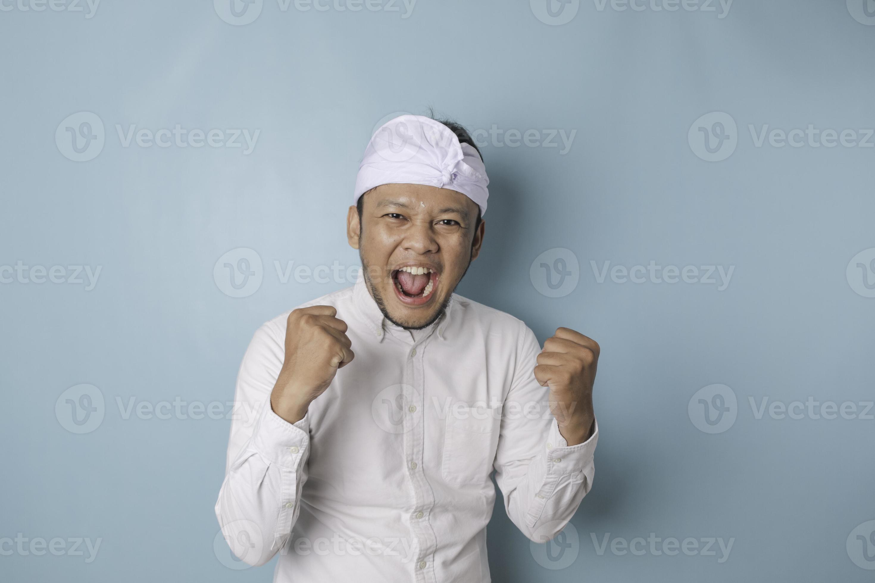 A young Balinese man with a happy successful expression wearing udeng