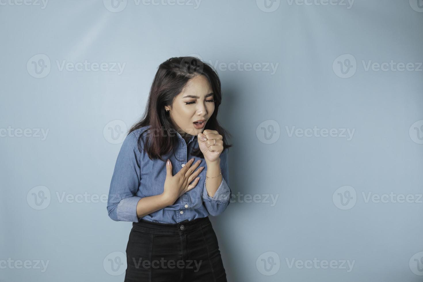 Sick young Asian woman in blue shirt feeling unwell and coughing as symptom for cold or covid-19. photo