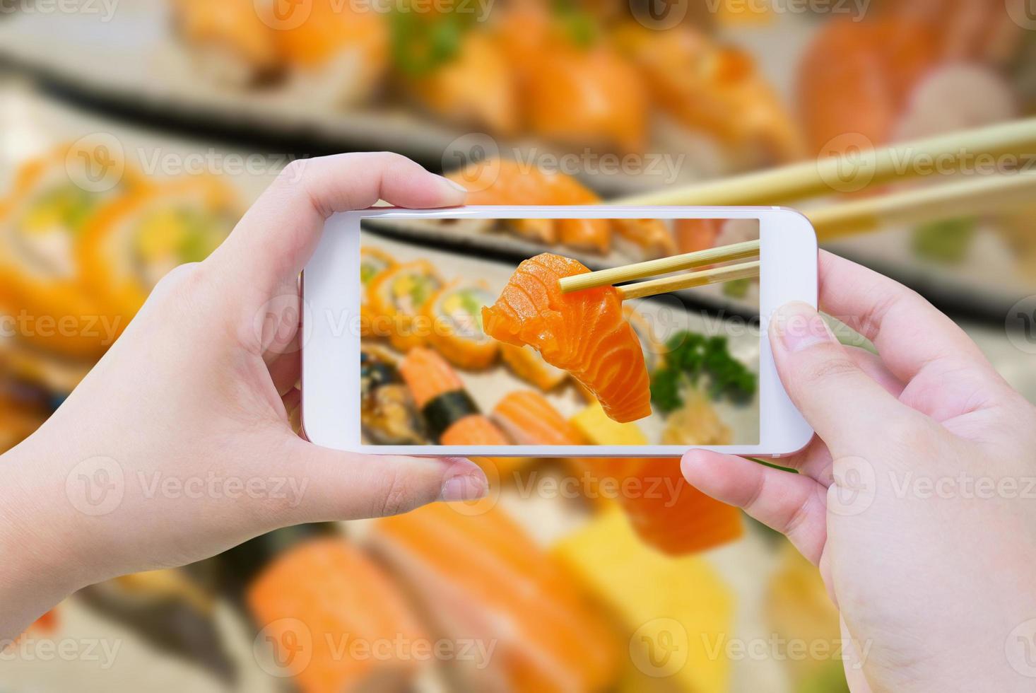 Taking photo of salmon sashimi in chopsticks