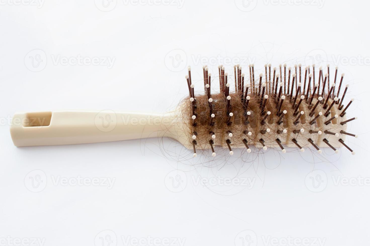 Cepillo de pelo con cabello perdido sobre fondo blanco. foto
