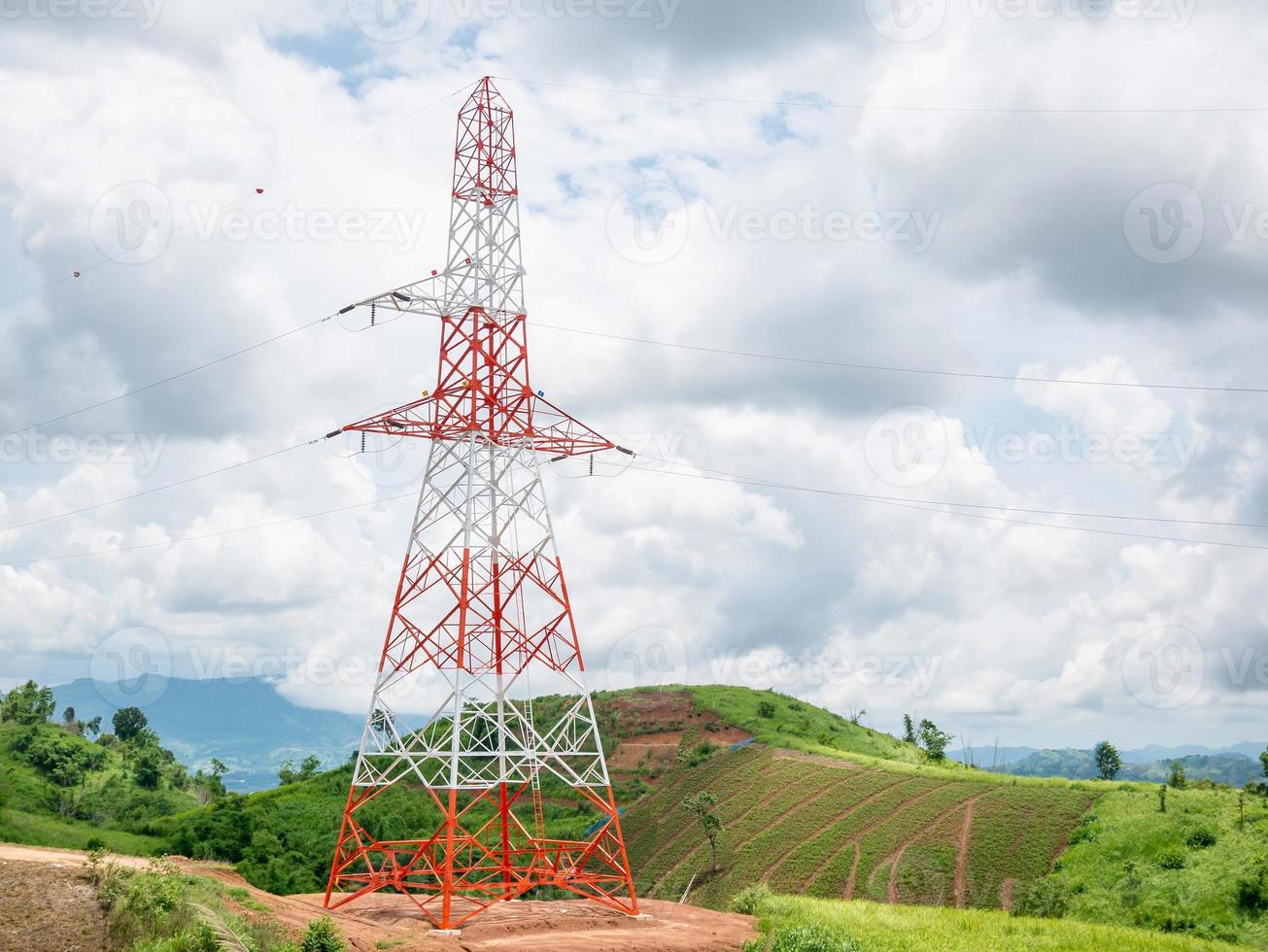 High voltage power lines tower on green mountain photo