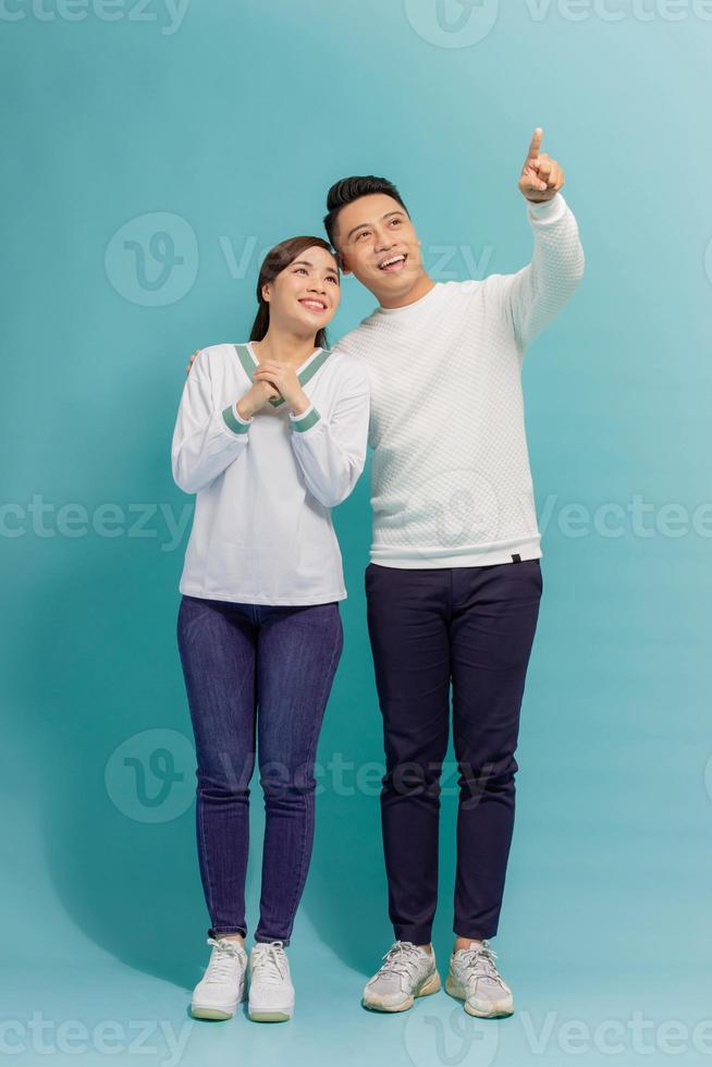 Young asian couple isolated on blue background pointing finger to the side photo