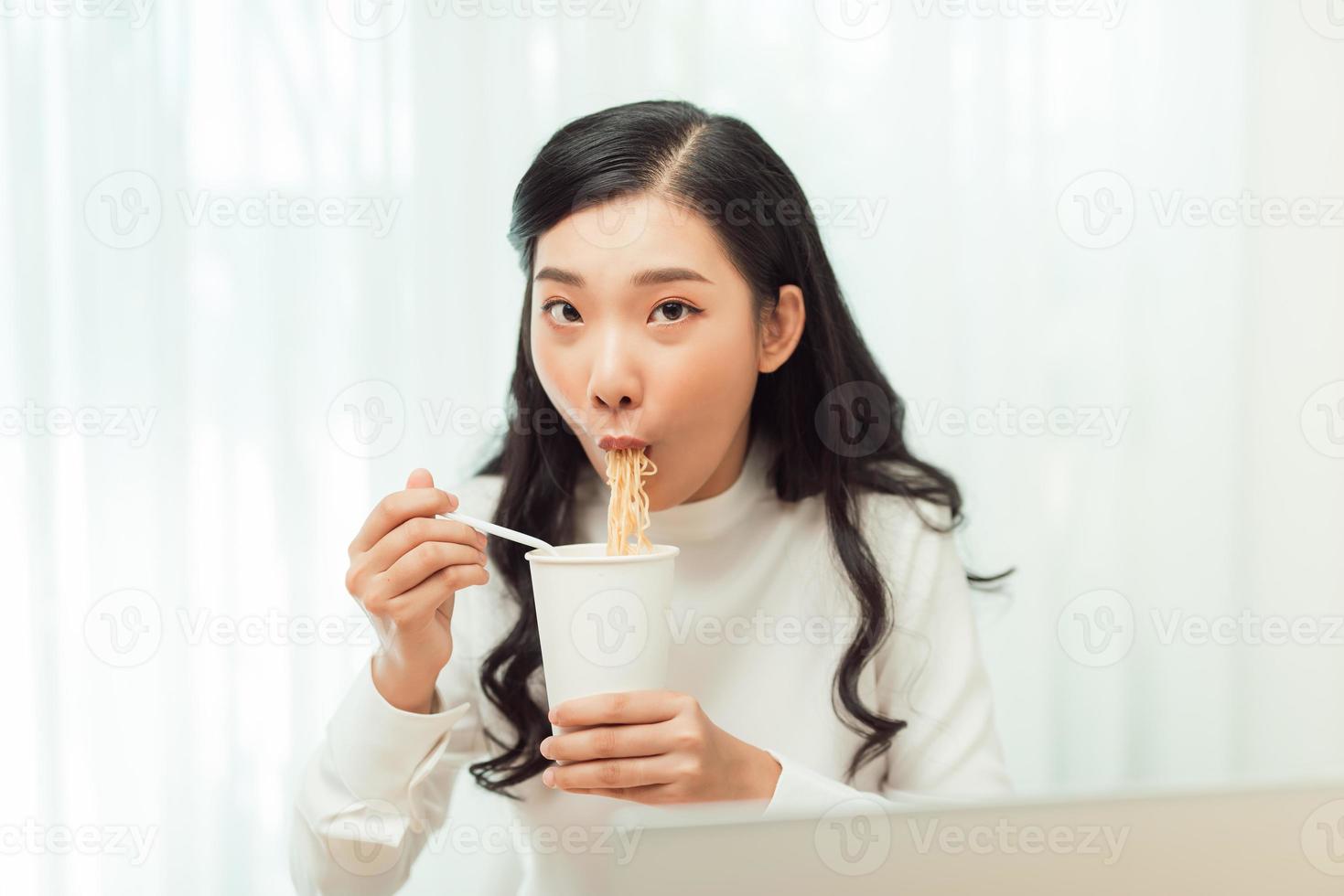 Late dinner. Girl eating instant noodles cup buy with great appetite. photo
