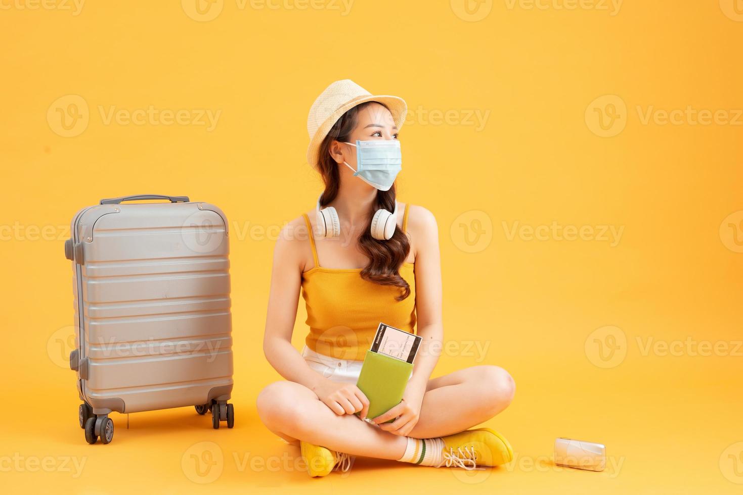 Young Asian female tourist wearing mask of new normal lifestyle Carrying a backpack and passport to go to travel ,Protect yourself from virus photo