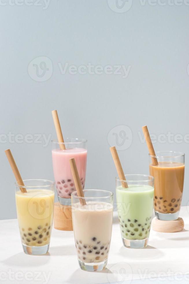 Five glasses of healthy milky boba or bubble tea flavored with fresh fruit and chocolate and served with traditional wide straws photo